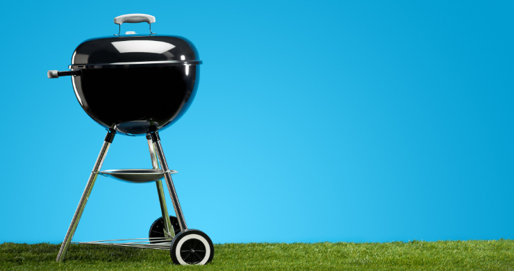 grill on grass against a blue sky
